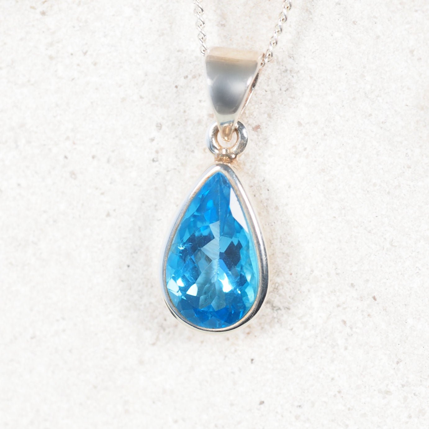 blue topaz pendant displayed in a silver frame bezel setting
