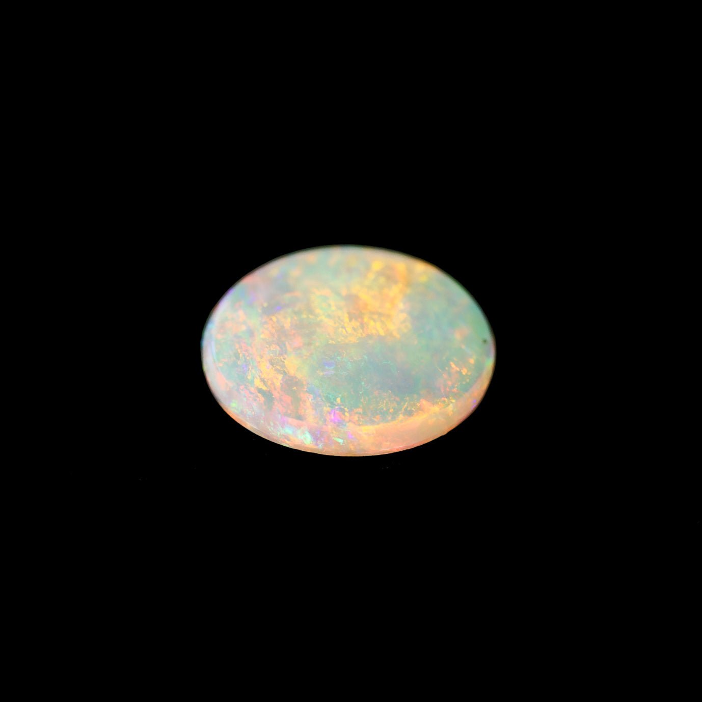 Opal gemstone with multicolored play of light on a black background