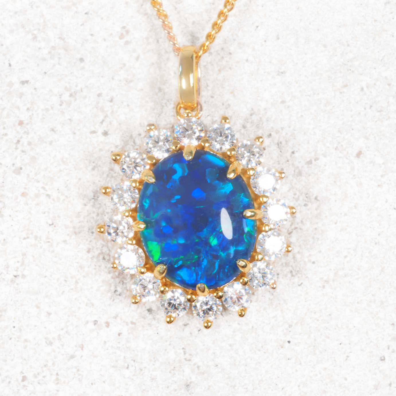 Blue opal pendant in a gold plated silver setting and diamond accents on a white background