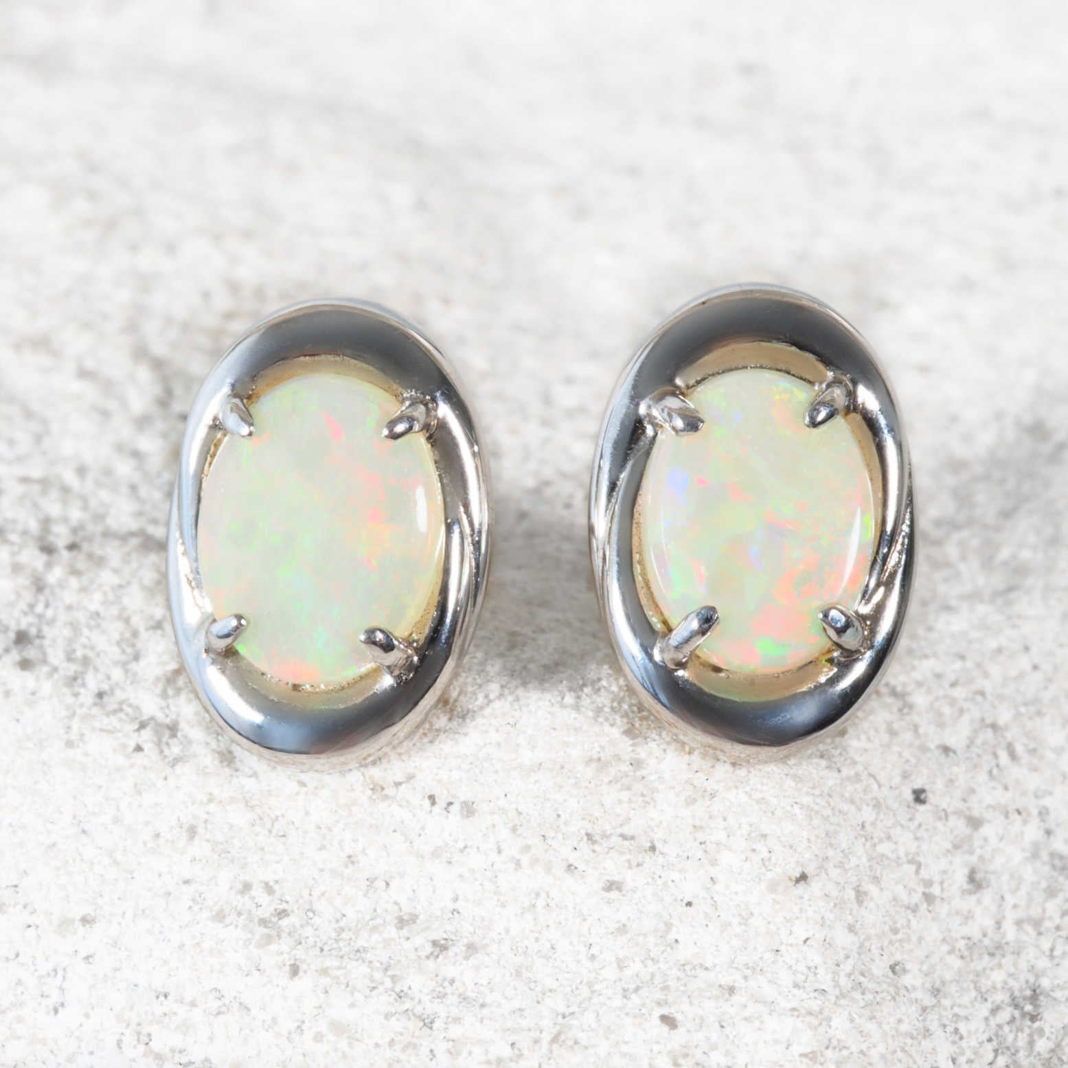 The ‘Raya’ opal stud earrings are crafted in sterling silver and claw-set with luminous oval solid crystal opals