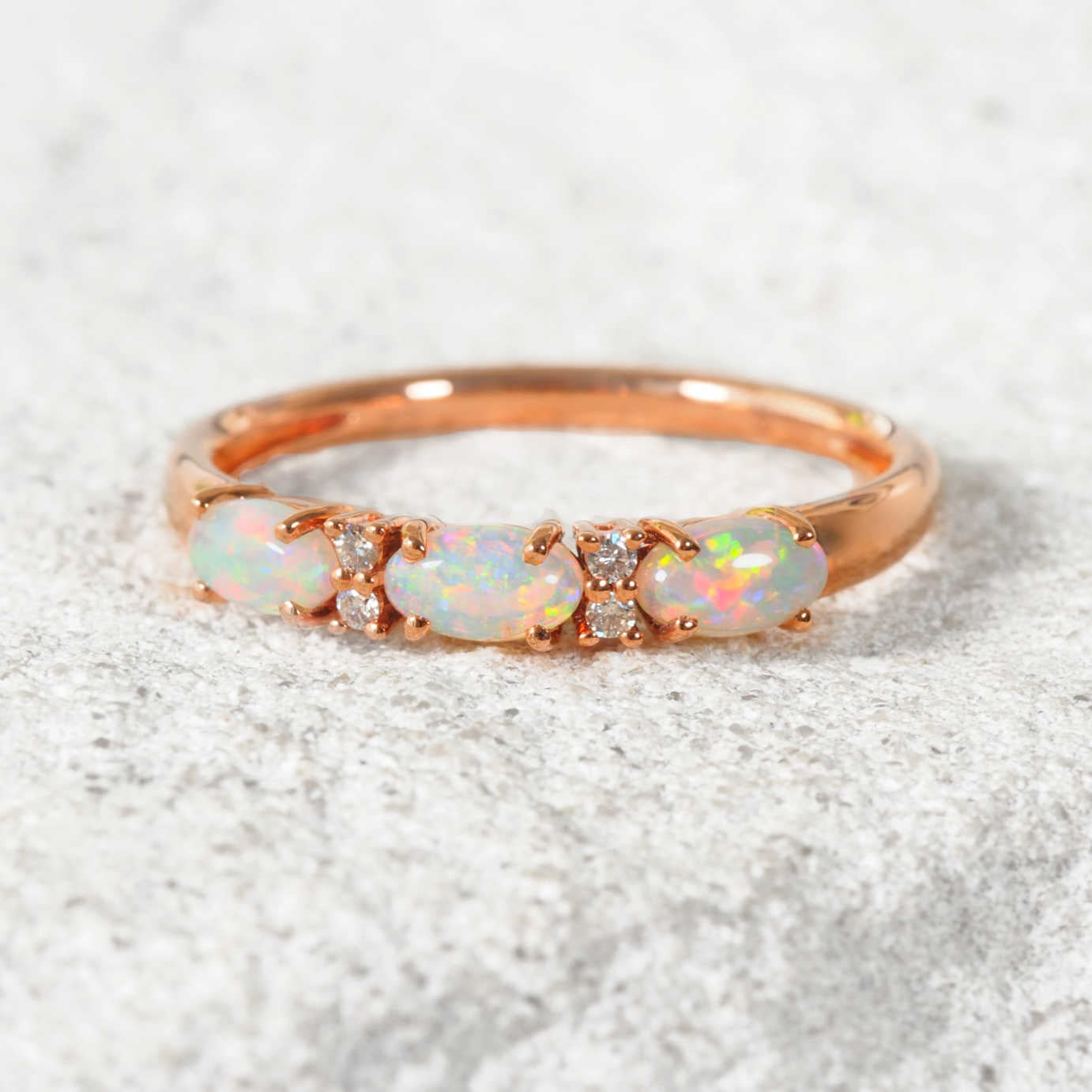 White opal Rose gold ring with opal stones on a textured white background