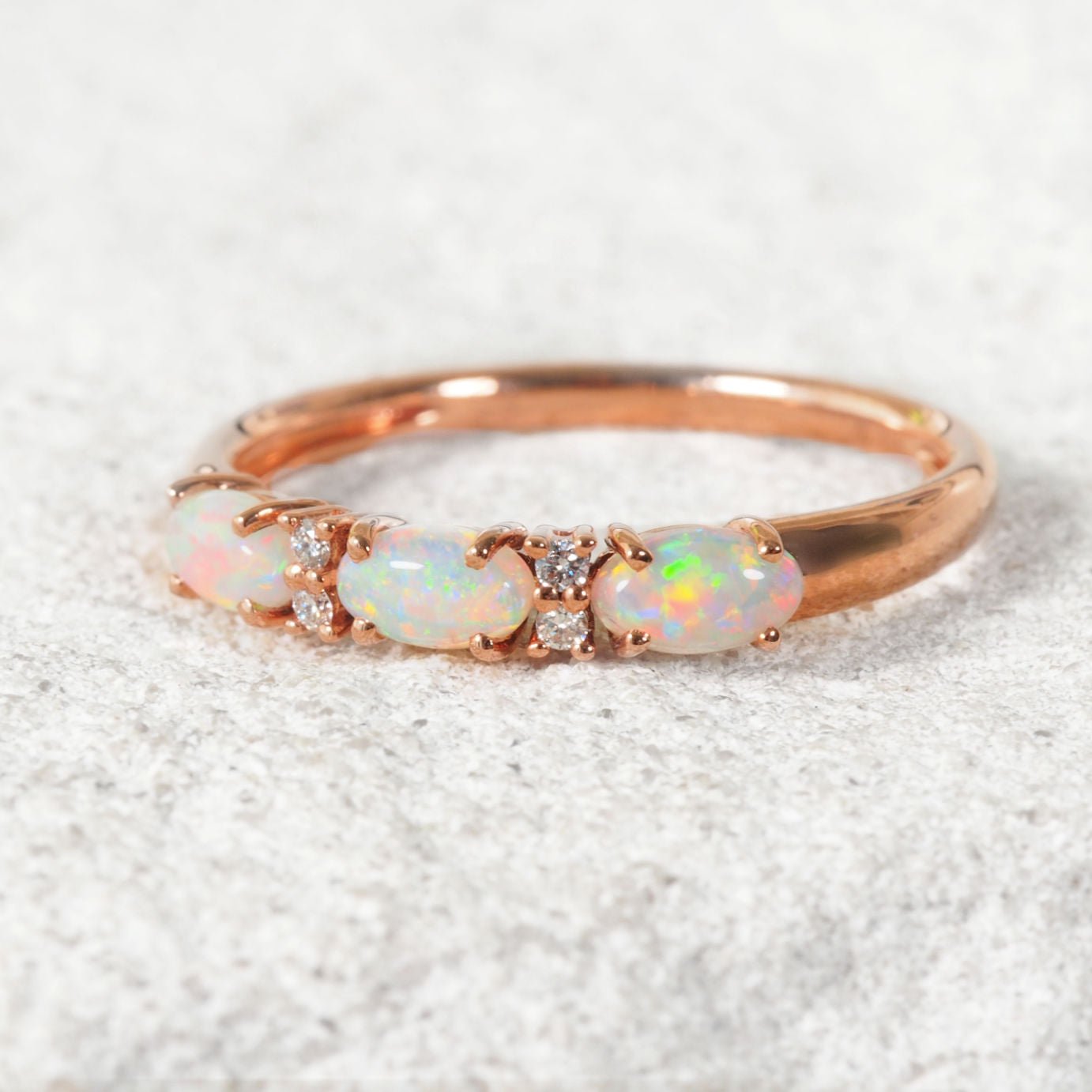 Rose gold ring with opal stones on a light background