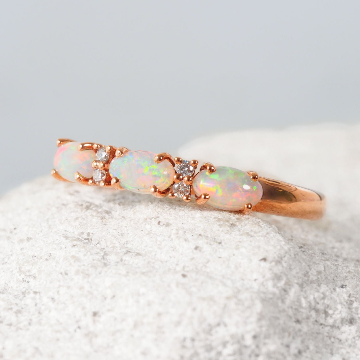 Rose gold opal ring with opal stones on a textured surface