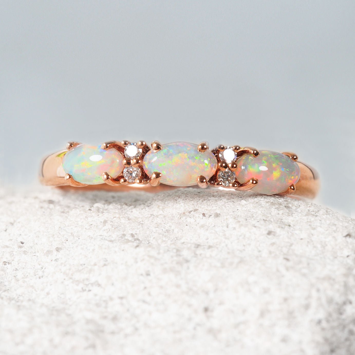 Ring with opal stones and rose gold band on a textured surface
