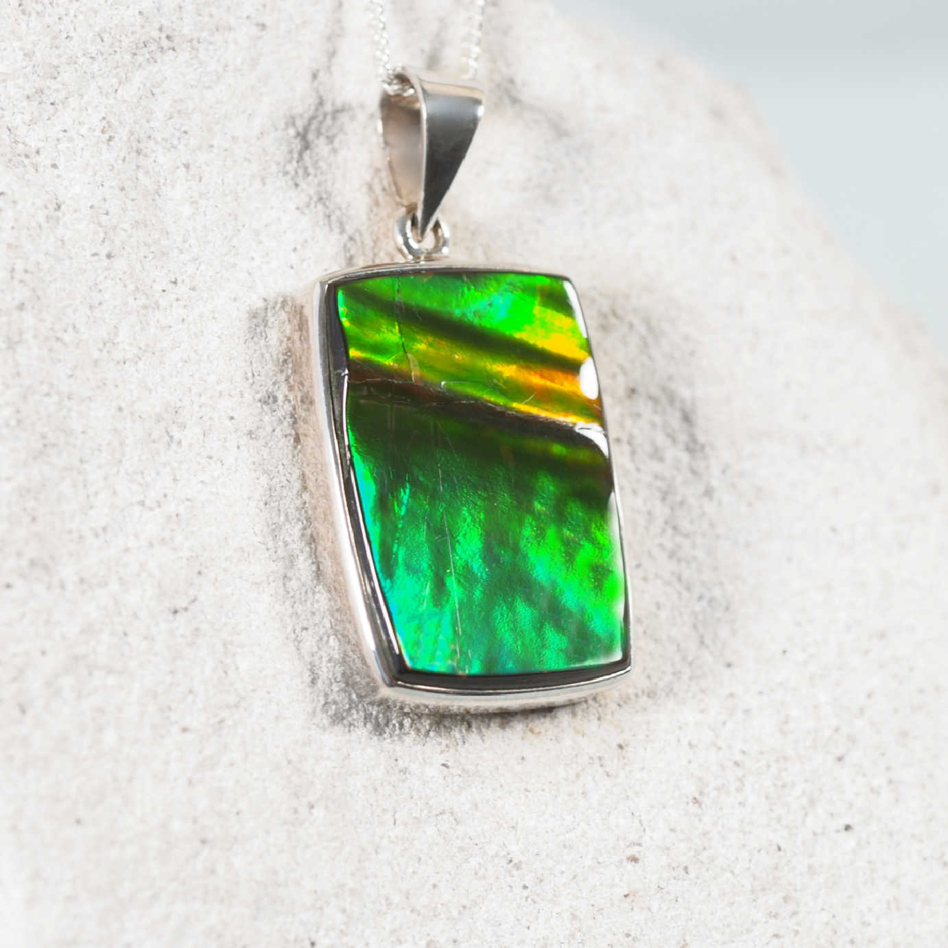 'Rylee' Ammolite pendant in silver featuring vibrant orange, gold, and green colors with a unique shimmering effect