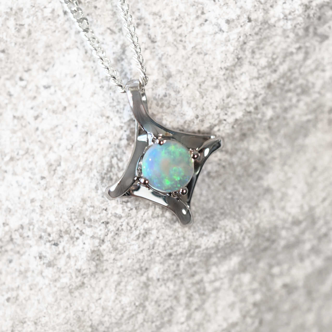 round green-blue opal set into a white gold frame necklace