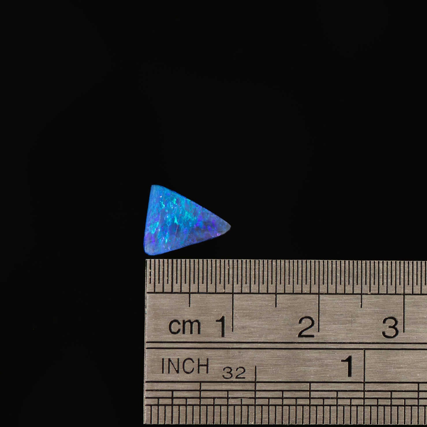 Shimmering triangular black opal with bright blue and green colour flashes against a dark body tone