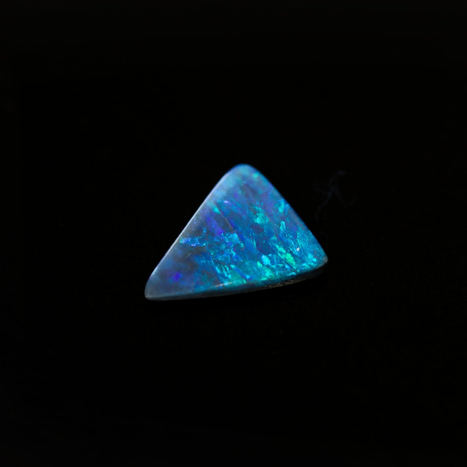 Australian black opal with stunning blue and green hues in a unique triangular shape