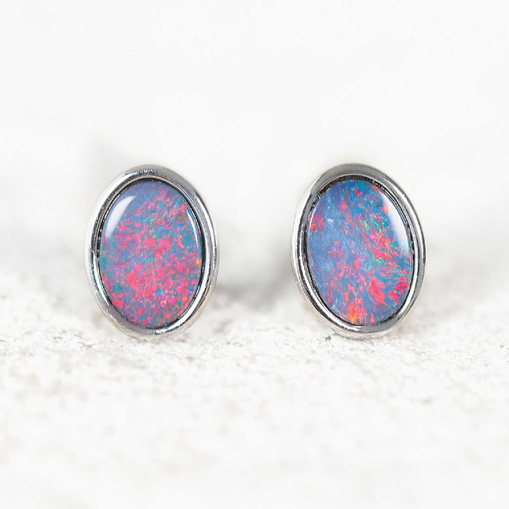 Pair of opal stud earrings with silver setting on a white background