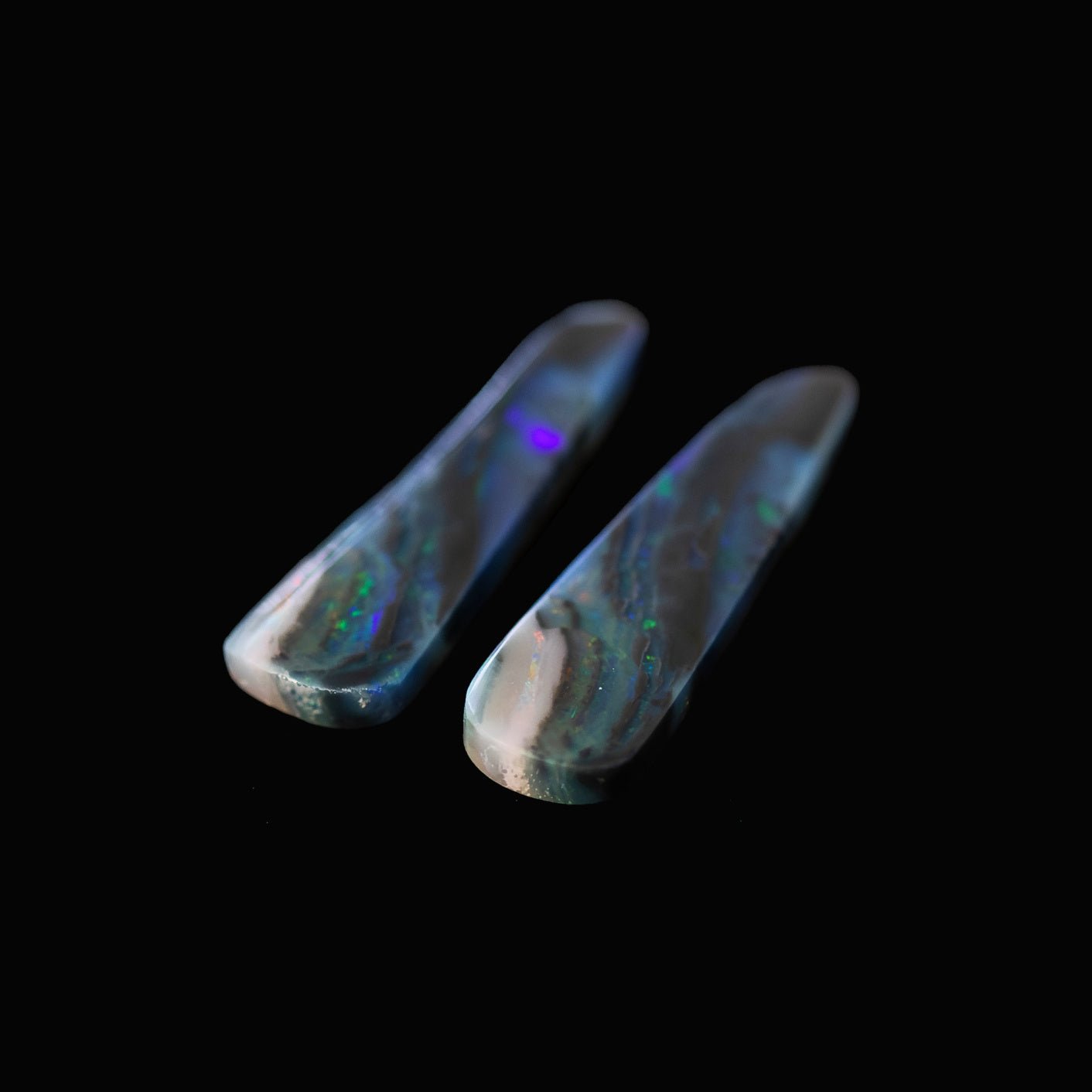 Two solid opal stones on a black background