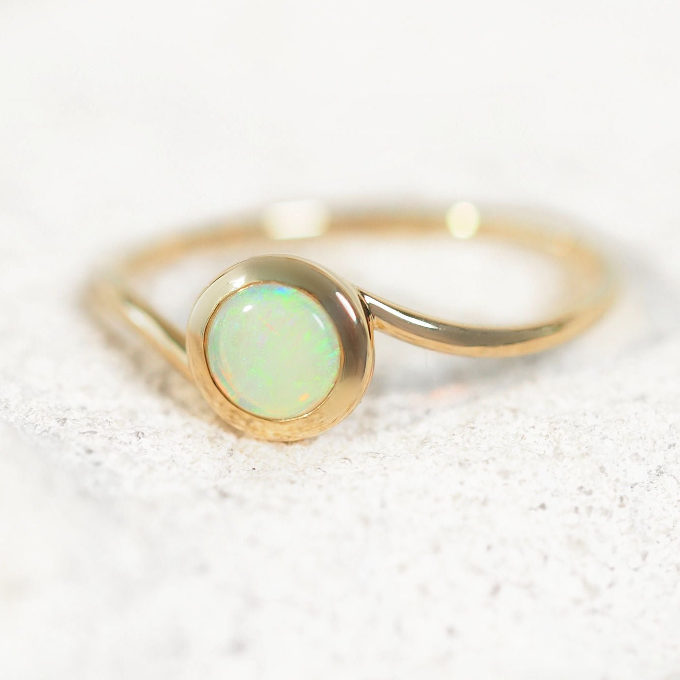 Gold ring with a green opal stone on a light background