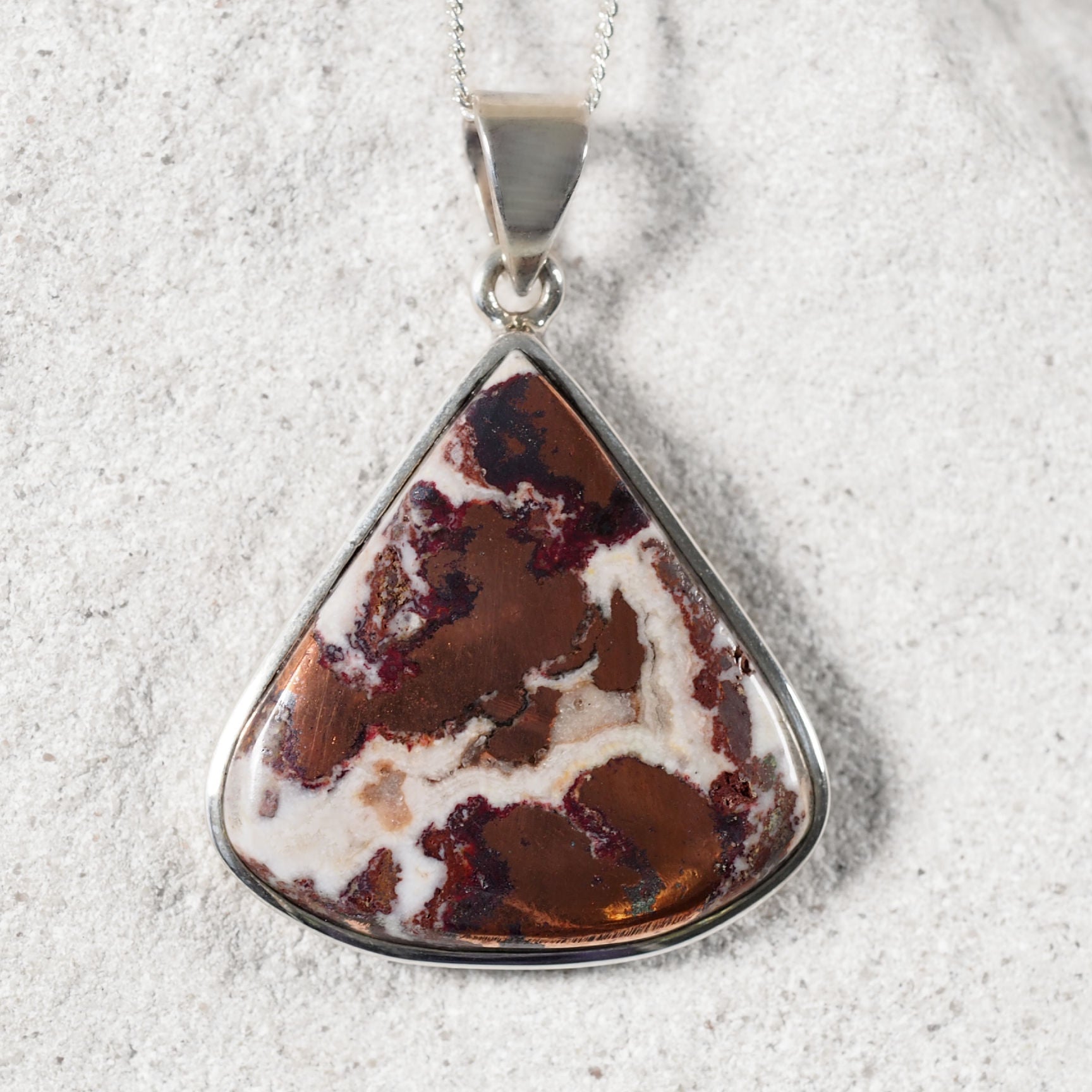 Polished silver teardrop pendant featuring natural Copper Dolomite with warm, multi-toned patterns