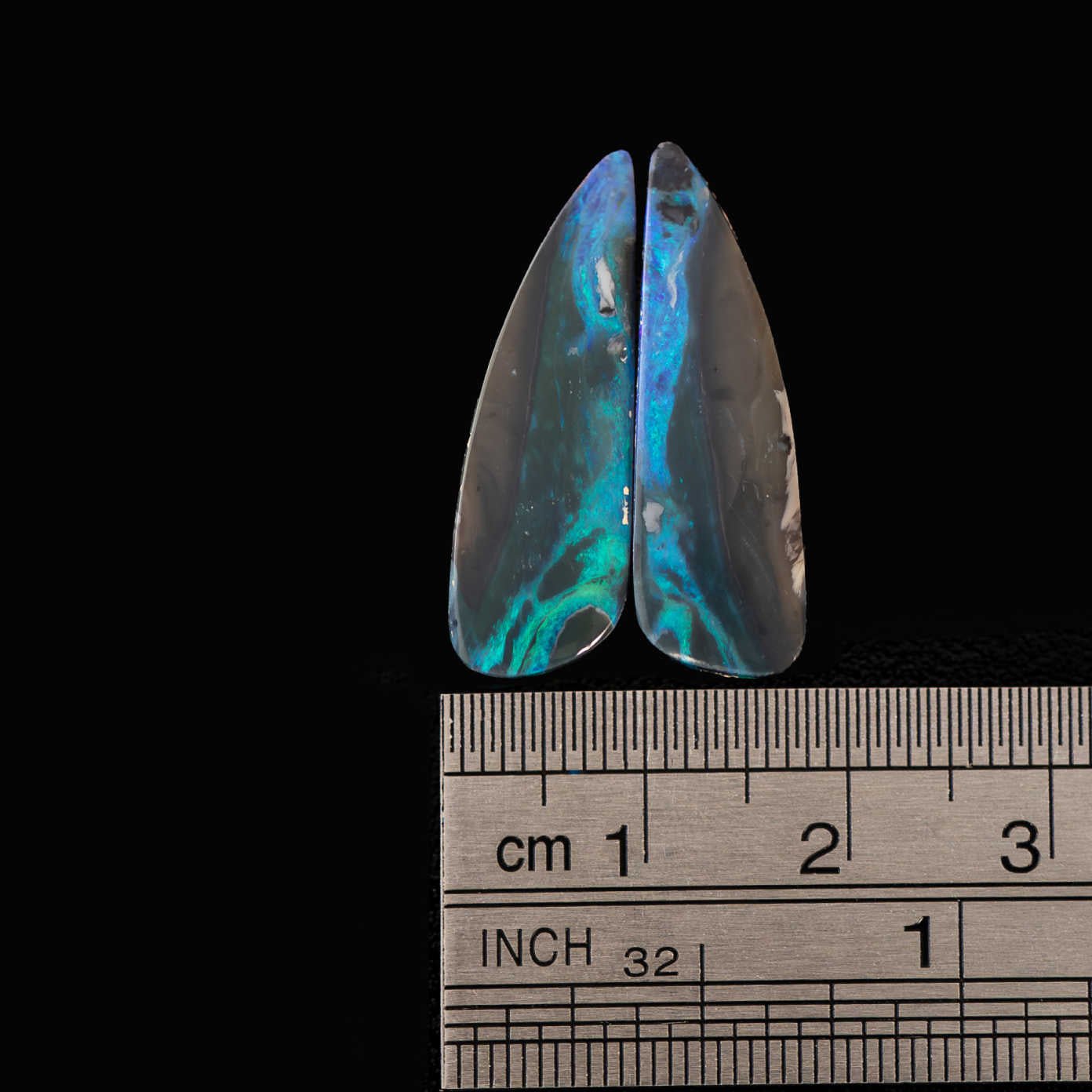 Black lightning ridge opal stones with a metal ruler