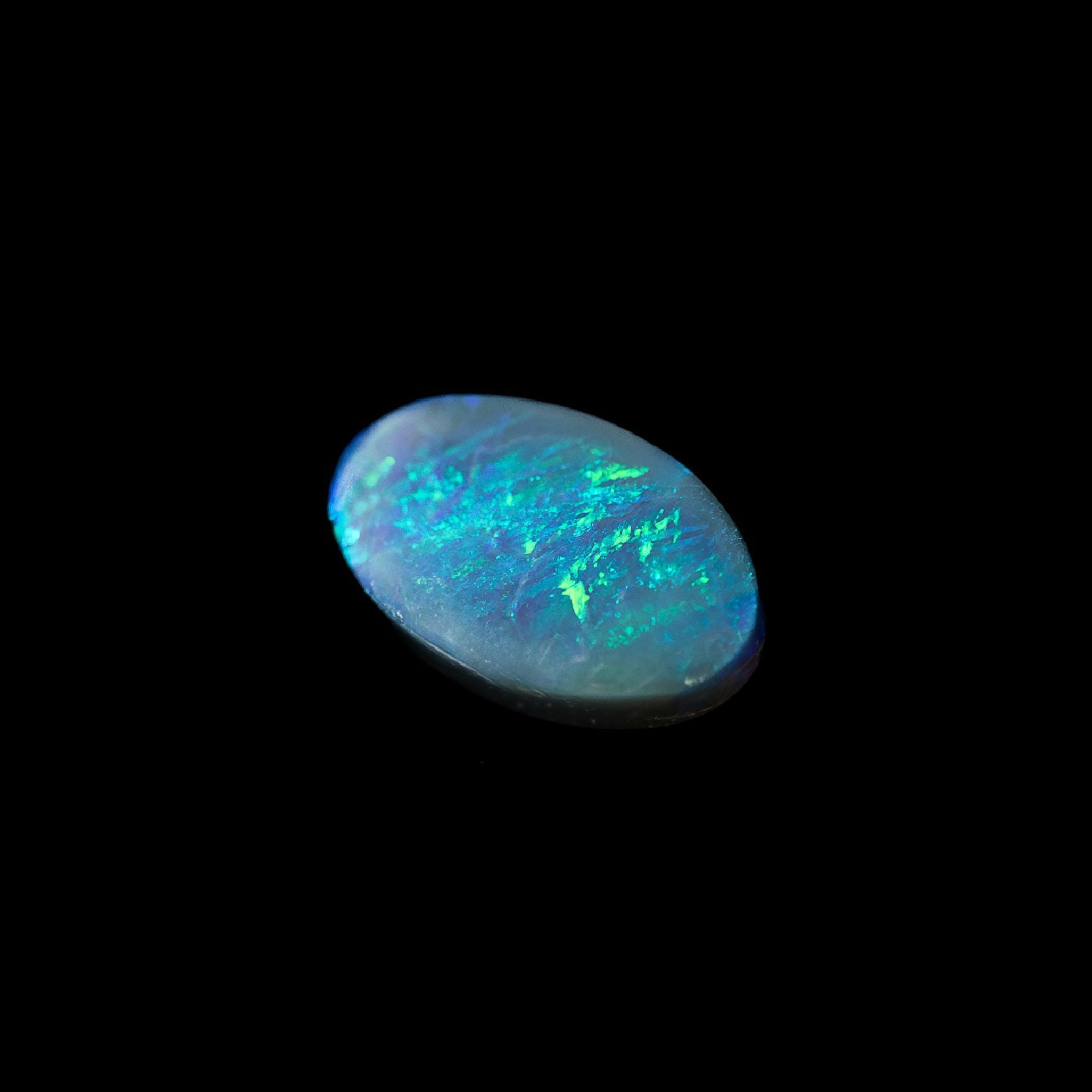 Loose semi-black opal stone showing bright play-of-colour in blue and green