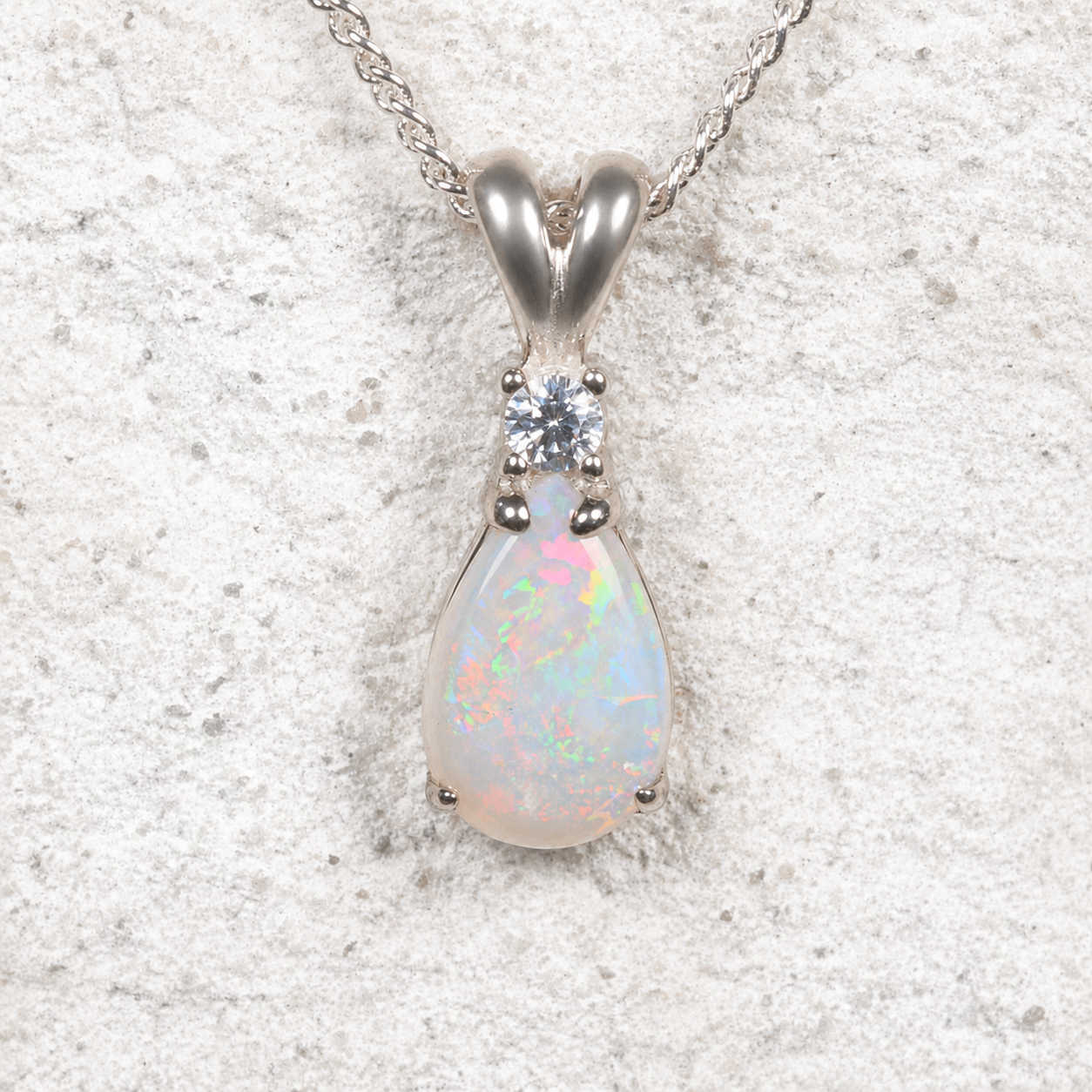 Opal pendant necklace with a silver chain on a textured white background