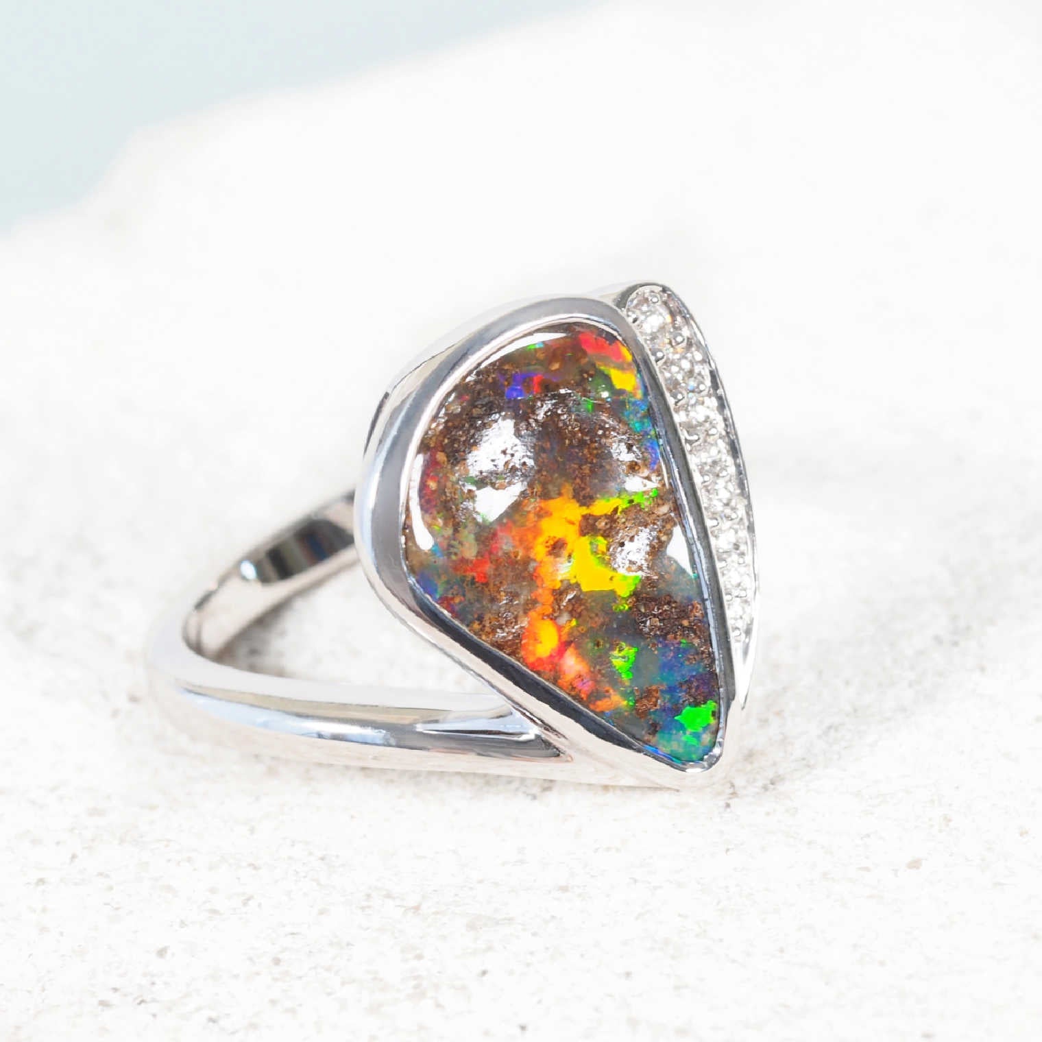 Triangular Queensland boulder opal ring showing vivid blue, green and red play-of-colour