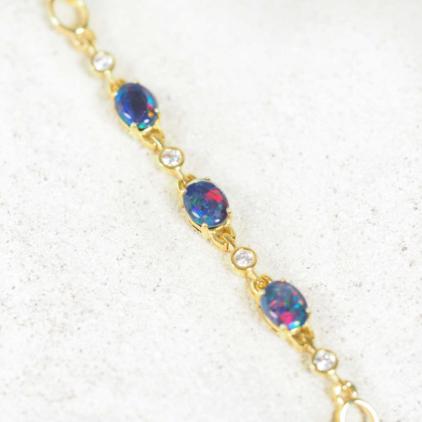 Gold bracelet with triplet opal stones on a white background