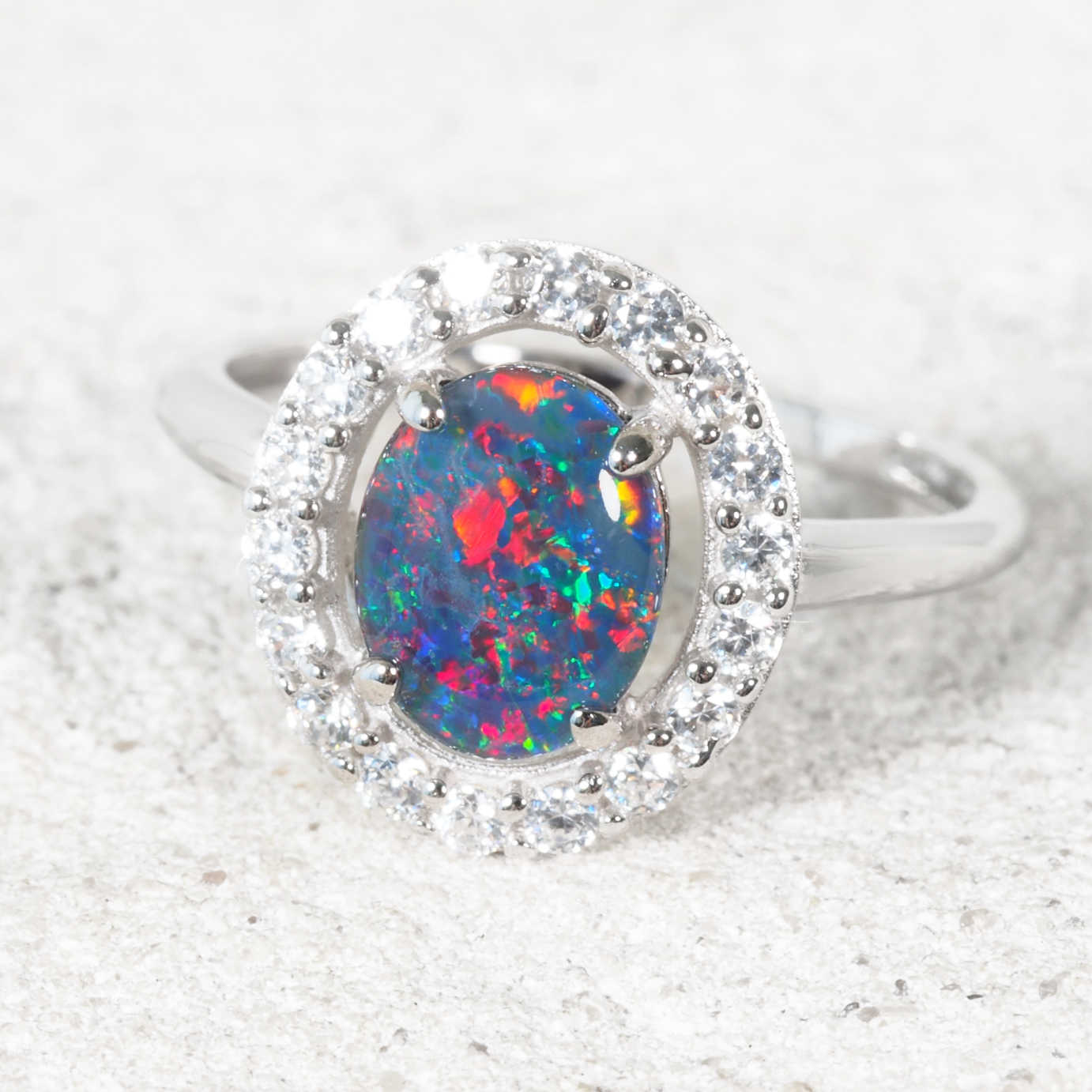 Ring with a colorful opal stone and diamond-like stones on a white background