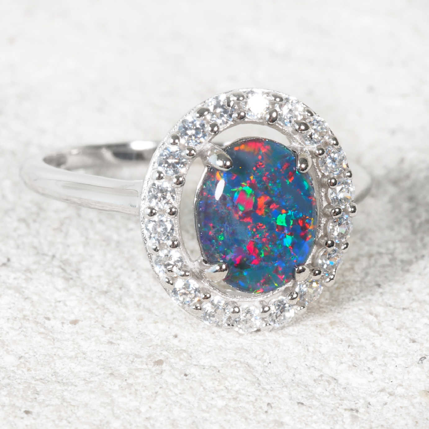 Silver opal ring with a diamante halo on a white backdrop