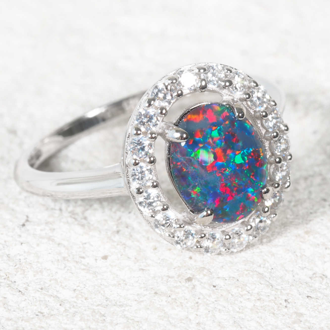 Silver ring with a colorful opal stone on a white background