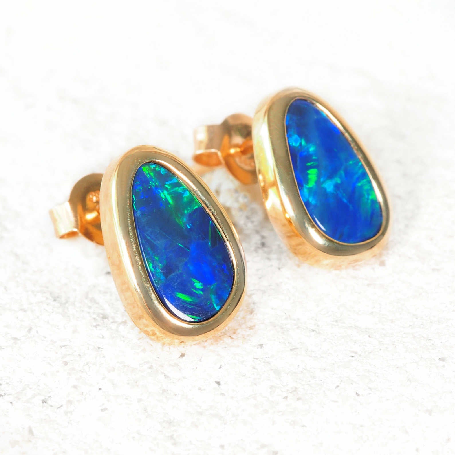 Gold earrings with blue opal stones on a white background