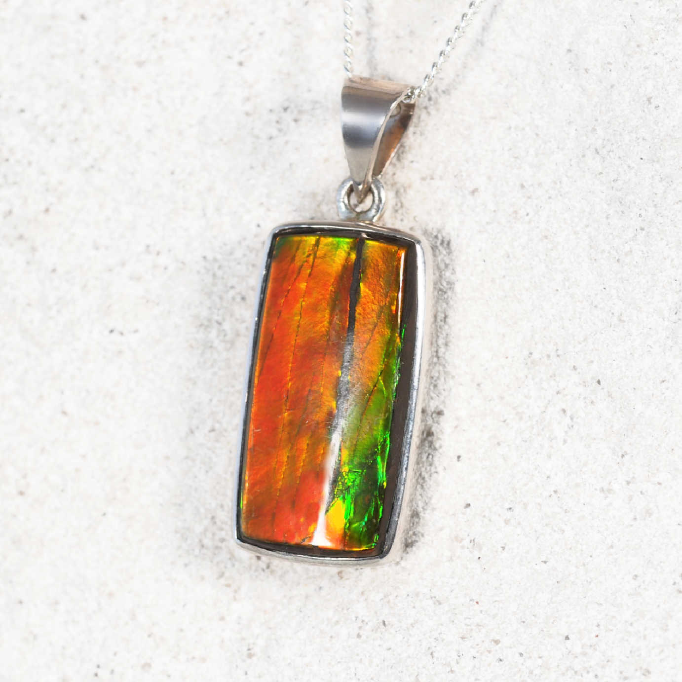 'Taylah' Ammolite pendant with rectangular stone set in silver, showing vivid orange, green.