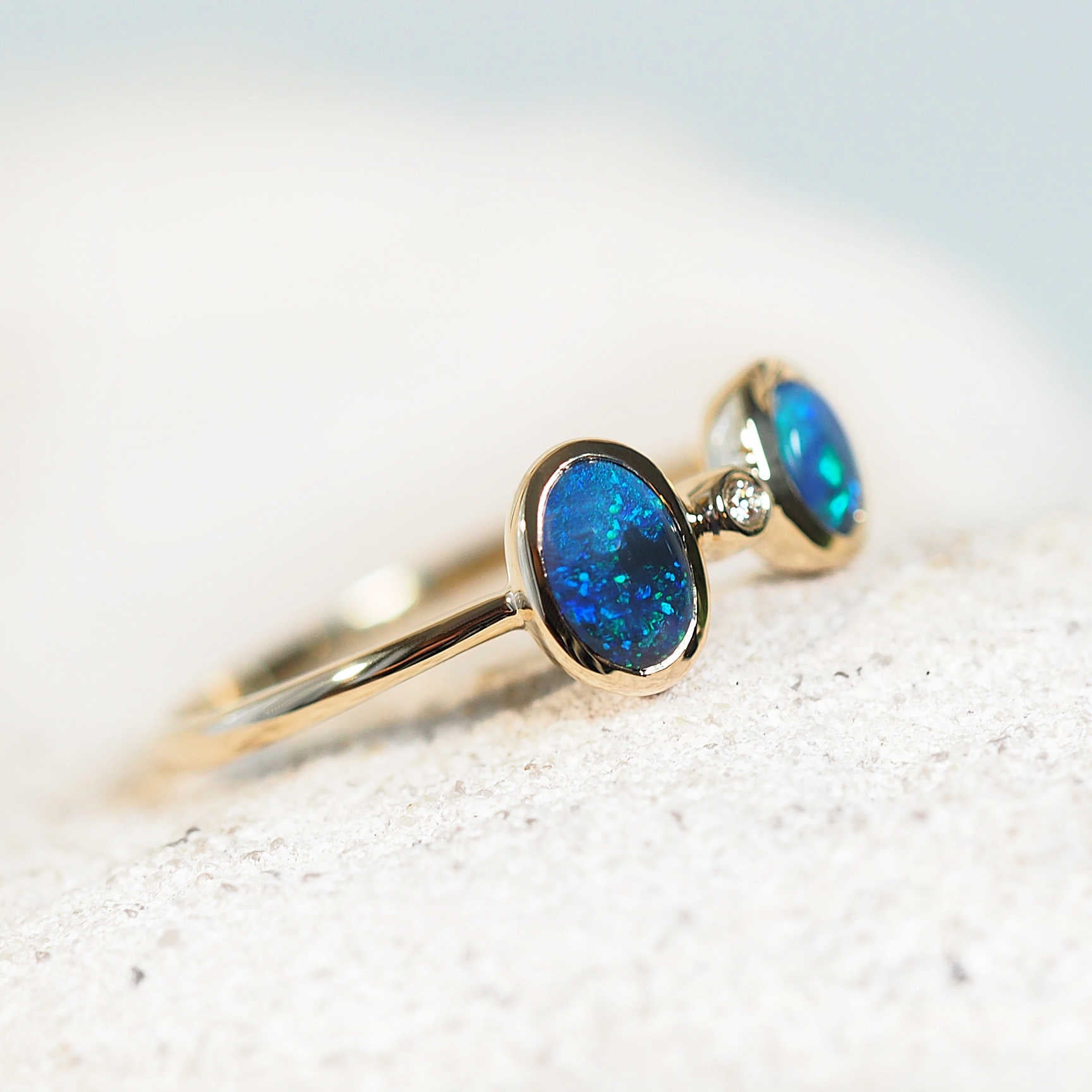 blue and green black opal ring set in 14ct yellow god with one diamond