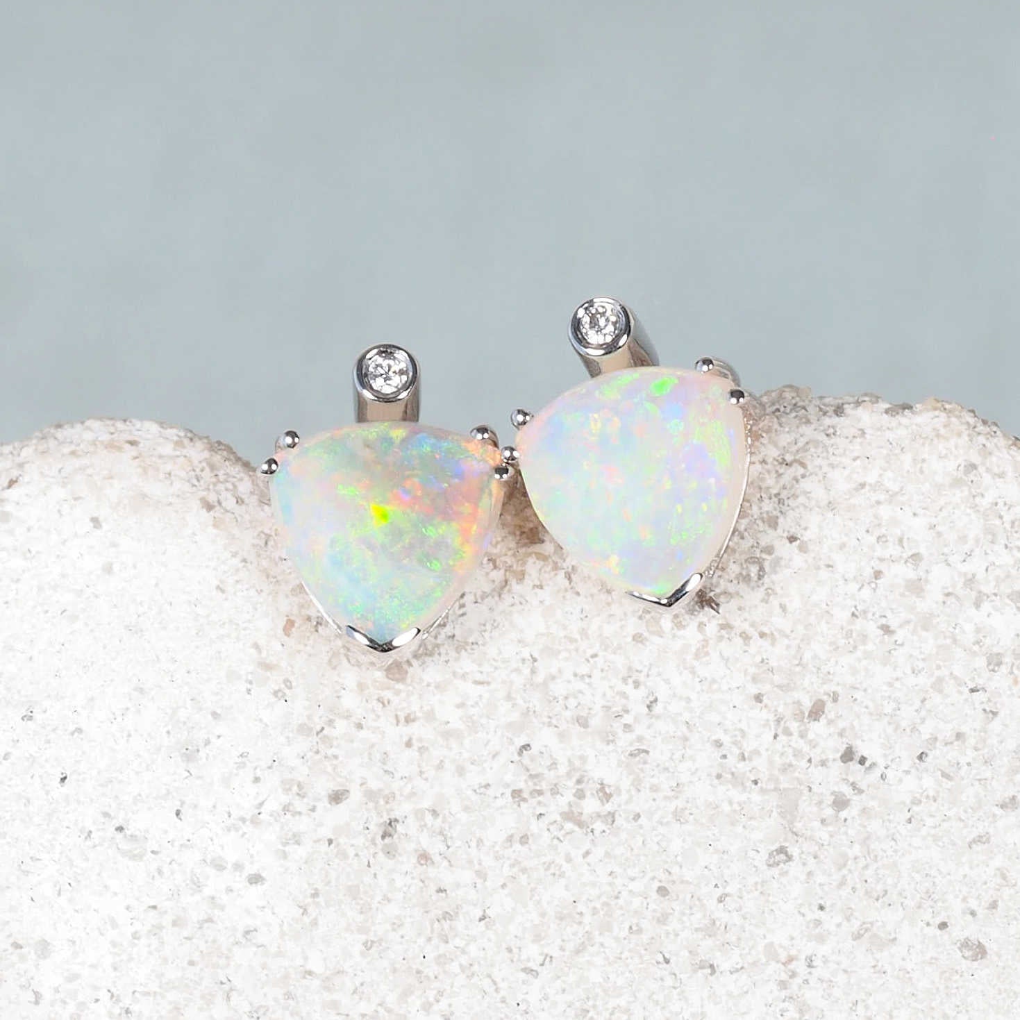 Close-up of 14ct white gold opal earrings with green, blue, and pink flashes from Coober Pedy opals