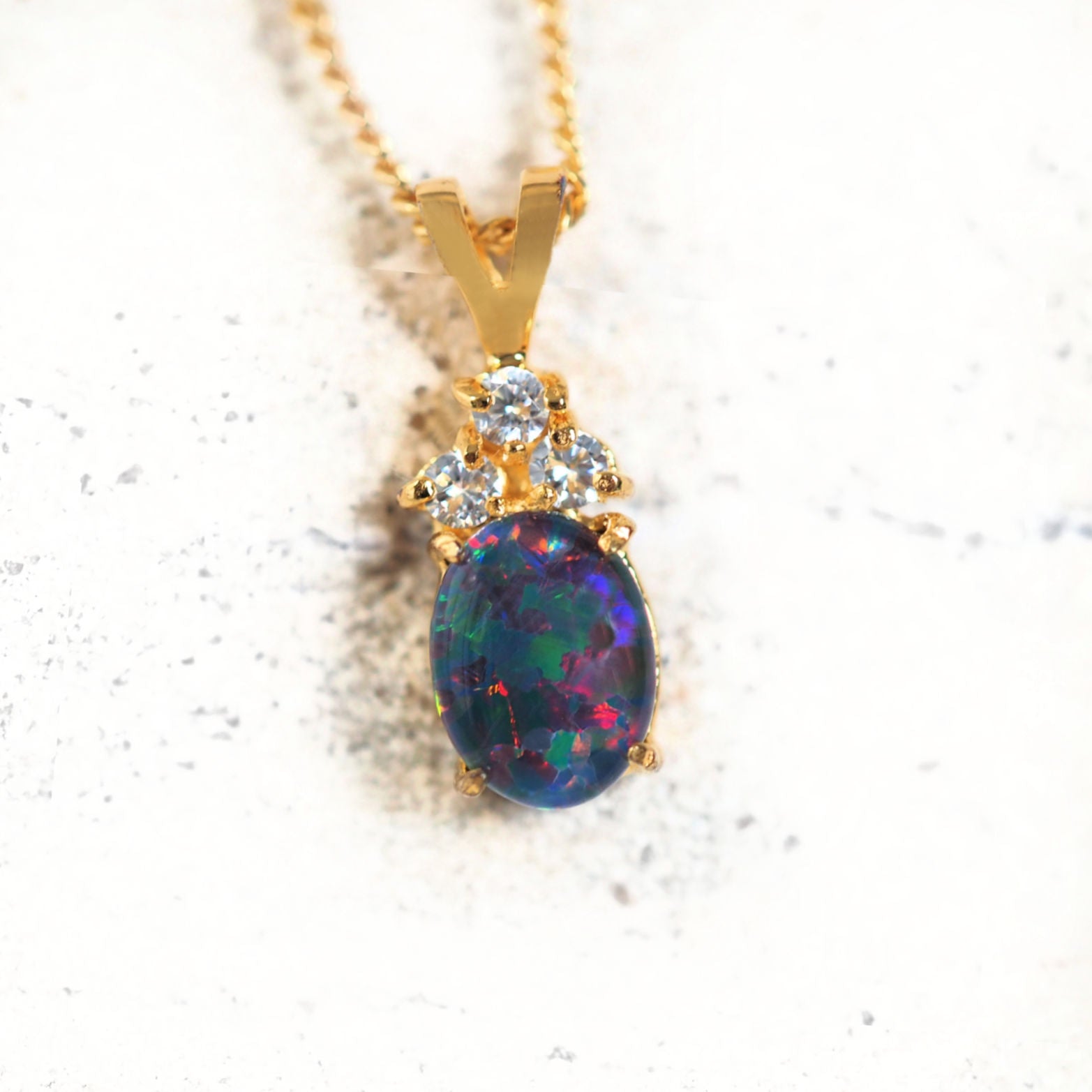 Gold-plated silver opal pendant with an oval-shaped Australian triplet opal and three sparkling cubic zirconias.
