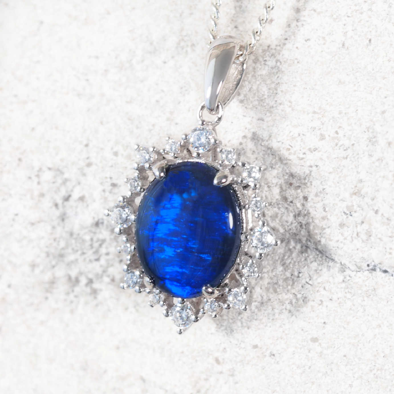 ‘Victoria Blue’ sterling silver opal pendant with claw-set oval Australian triplet opal in vivid blue tones and halo of 16 sparkling cubic zirconias