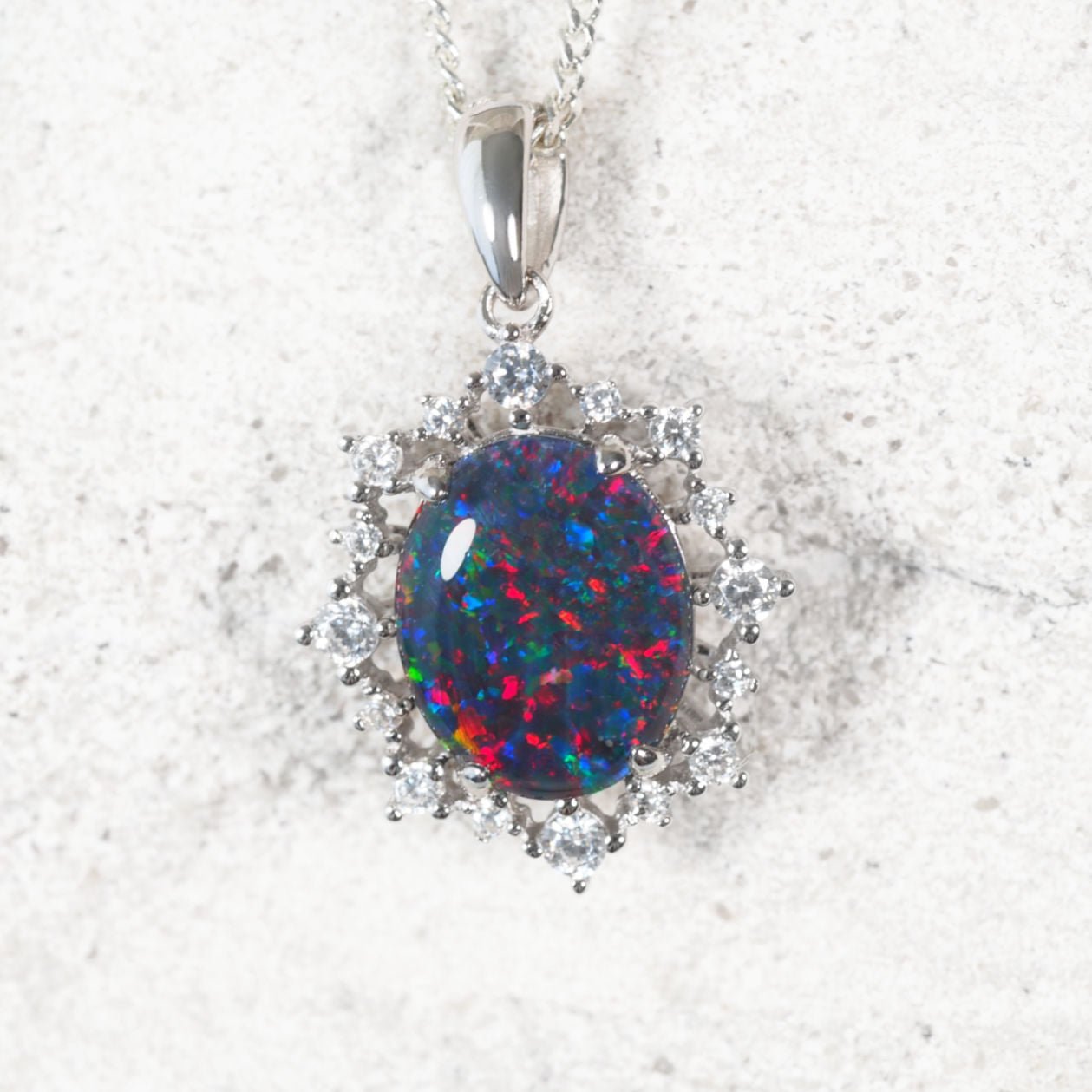 ‘Victoria’ sterling silver opal pendant with claw-set oval Australian triplet opal in vibrant multi-colour tones and halo of 16 sparkling cubic zirconias