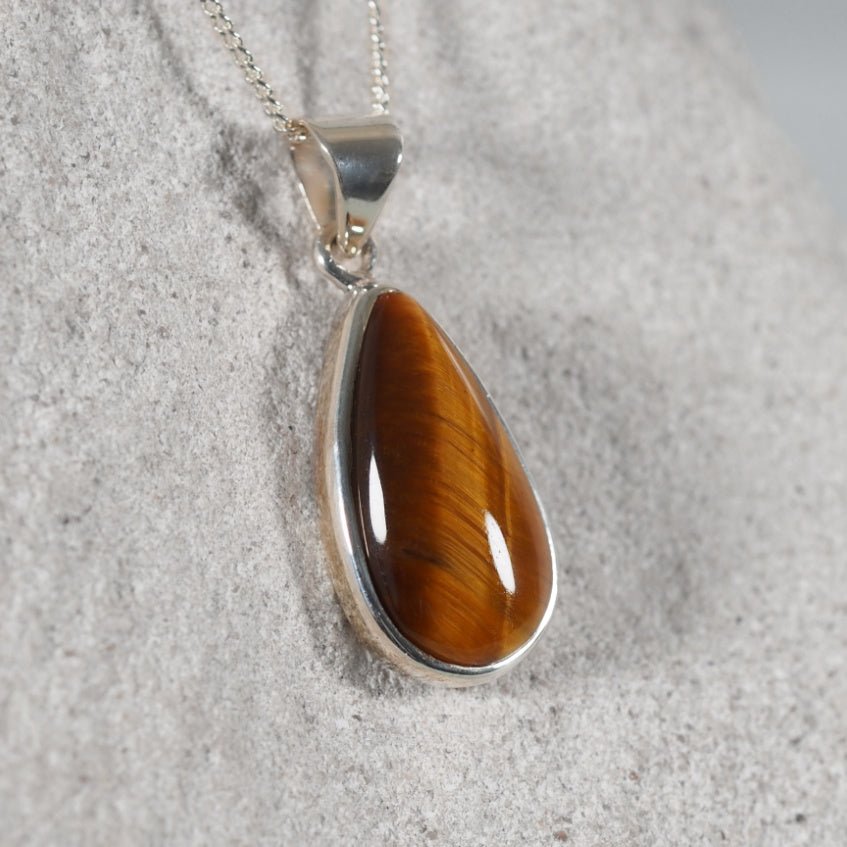 Teardrop-shaped tiger's eye pendant on a silver chain