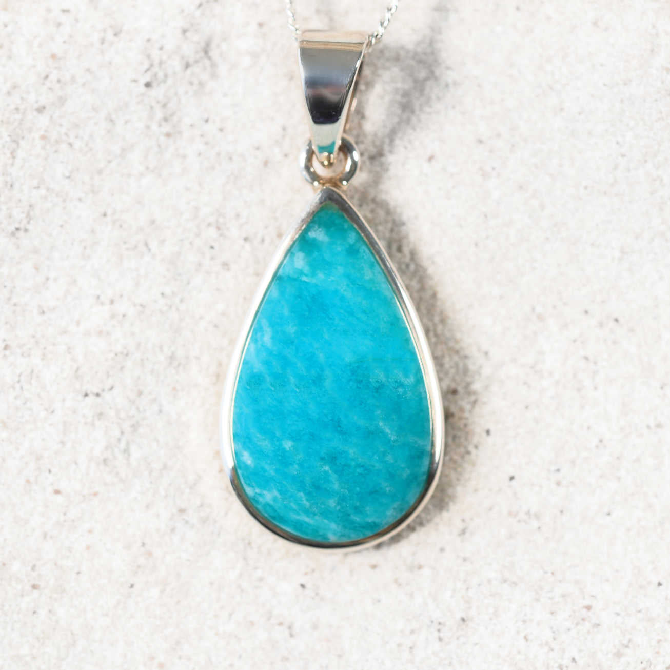 Close-up of the 'Yvonne' Amazonite teardrop pendant with blue-green cabochon in a polished silver frame
