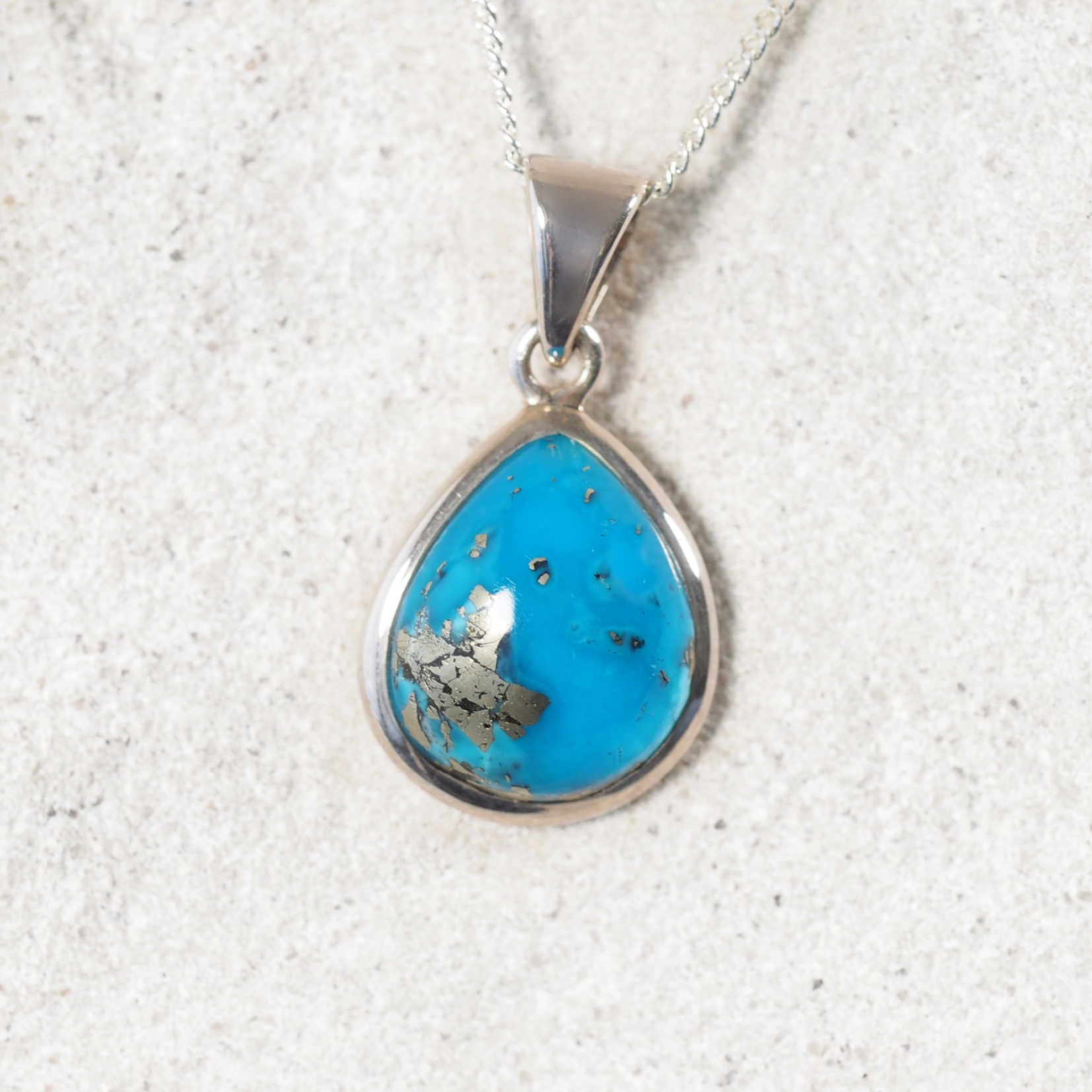 Turquoise pendant necklace on a textured white background