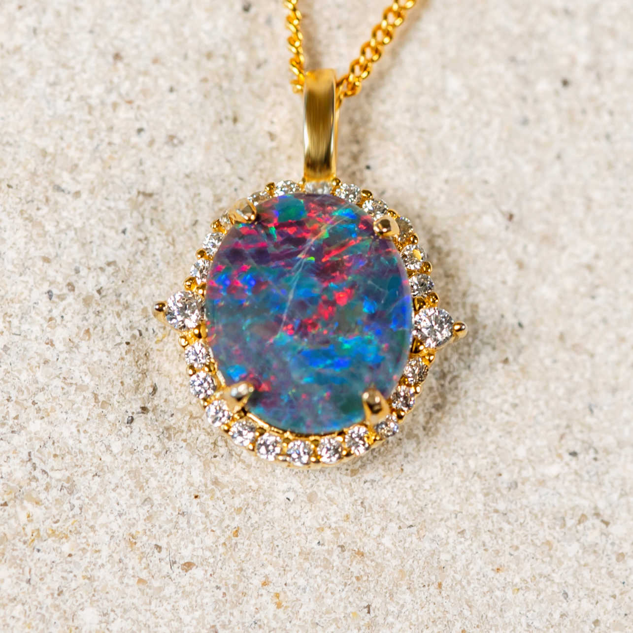 Sparkling gold plated sterling silver necklace pendant claw set with a brilliant multi-coloured round-oval Australian triplet opal surrounded by a halo of 24 cubic zirconias.