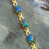 Gold plated sterling silver figure-8 design bracelet claw-set with five beautiful multi-colour oval triplet opals