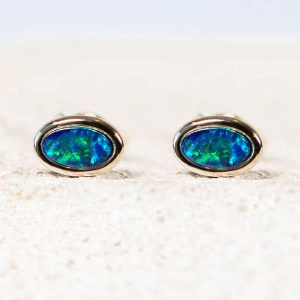 Classic sterling silver stud earrings bezel set with blue and green-coloured oval Australian triplet opals.